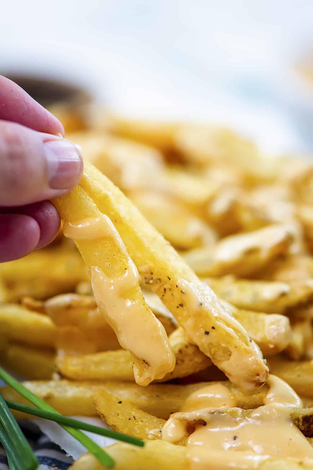 Hand holding 2 cheese fries.