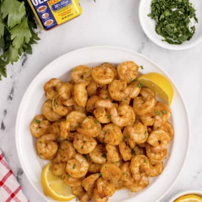 Shrimp on plate next to Old Bay seasoning.