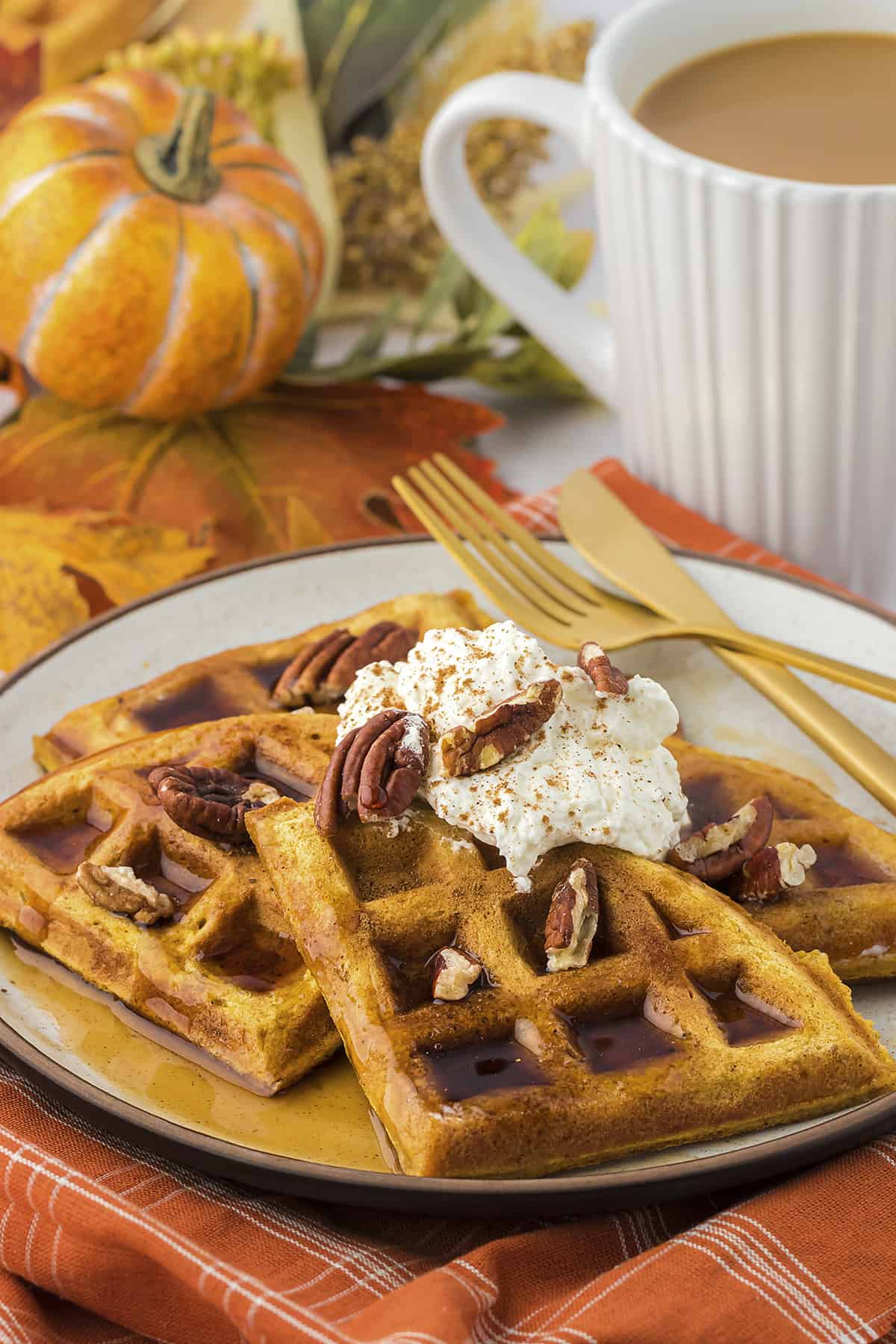 Pumpkin waffles topped with maple syrup, whipped cream, and pecans.