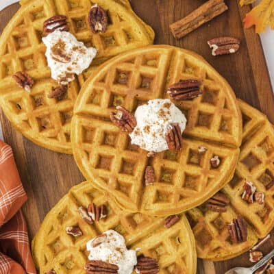 Overhead view of pumpkin waffles on wooden board.