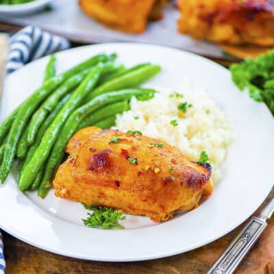 Baked harissa chicken on plate with vegetables.