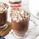 Mugs full of hot chocolate in front of crockpot and jar of Nutella.