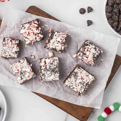 Chocolate peppermint fudge arranged on wooden cutting board.
