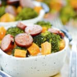 Sheet pan sausage and veggies in bowl of rice.