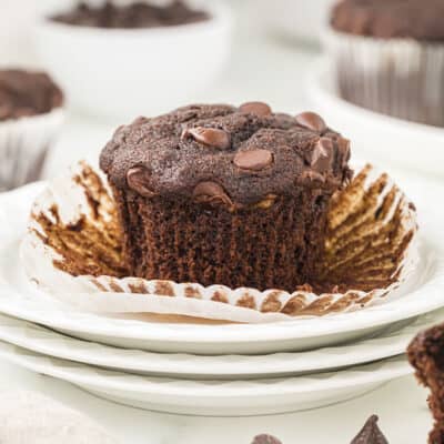 Banana chocolate muffin on stack of white plates.