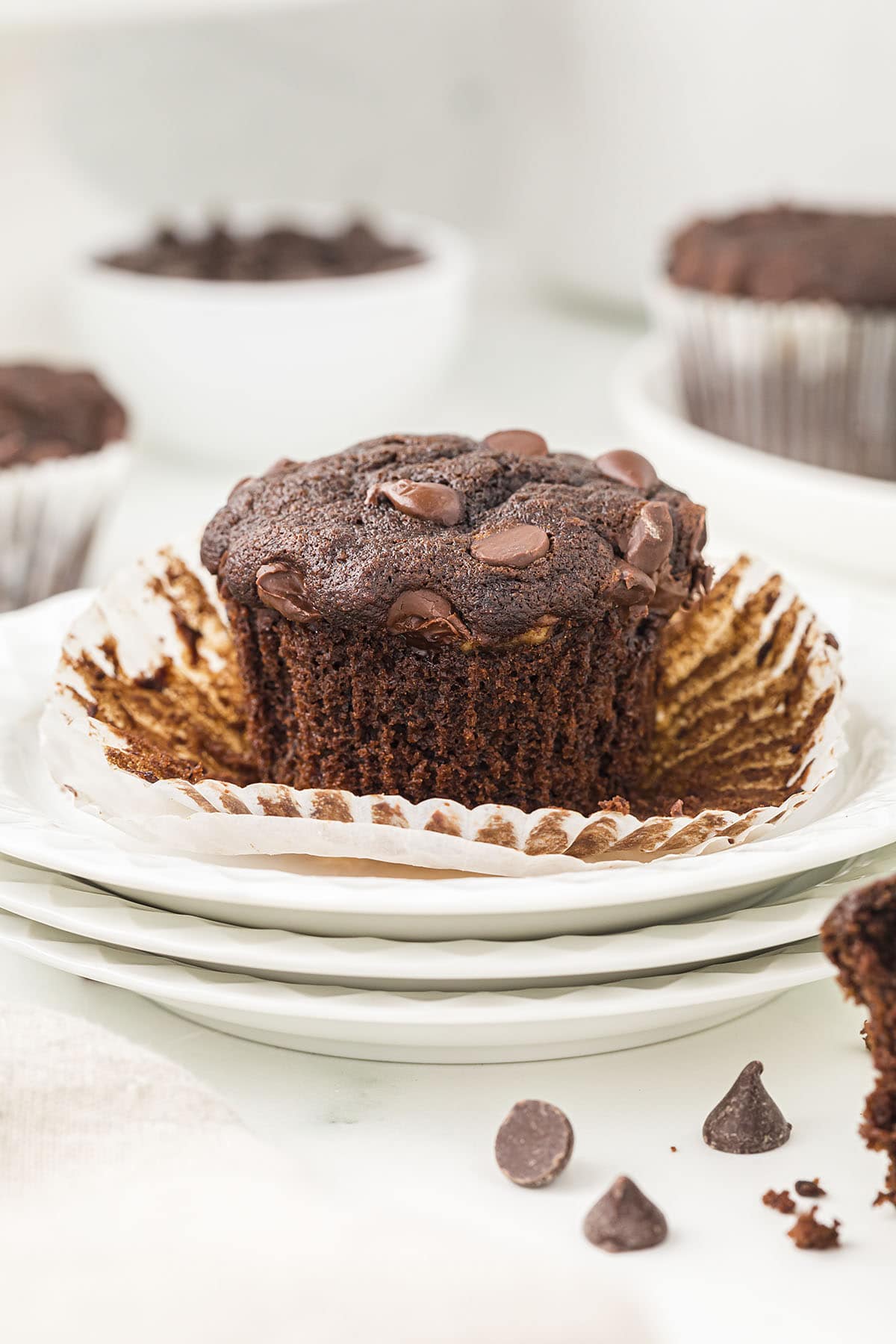 Banana chocolate muffin on stack of white plates.