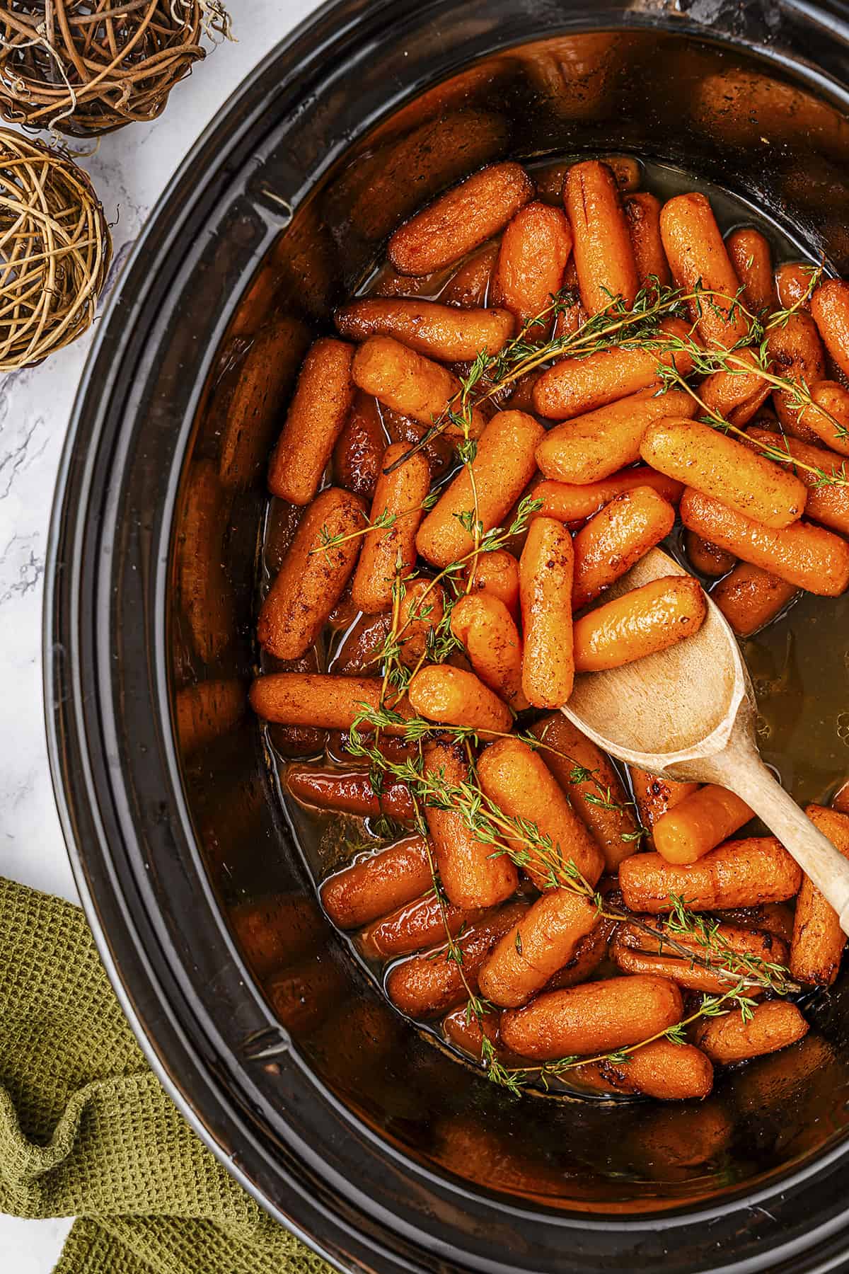 Carrots in crockpot with wooden spoon.