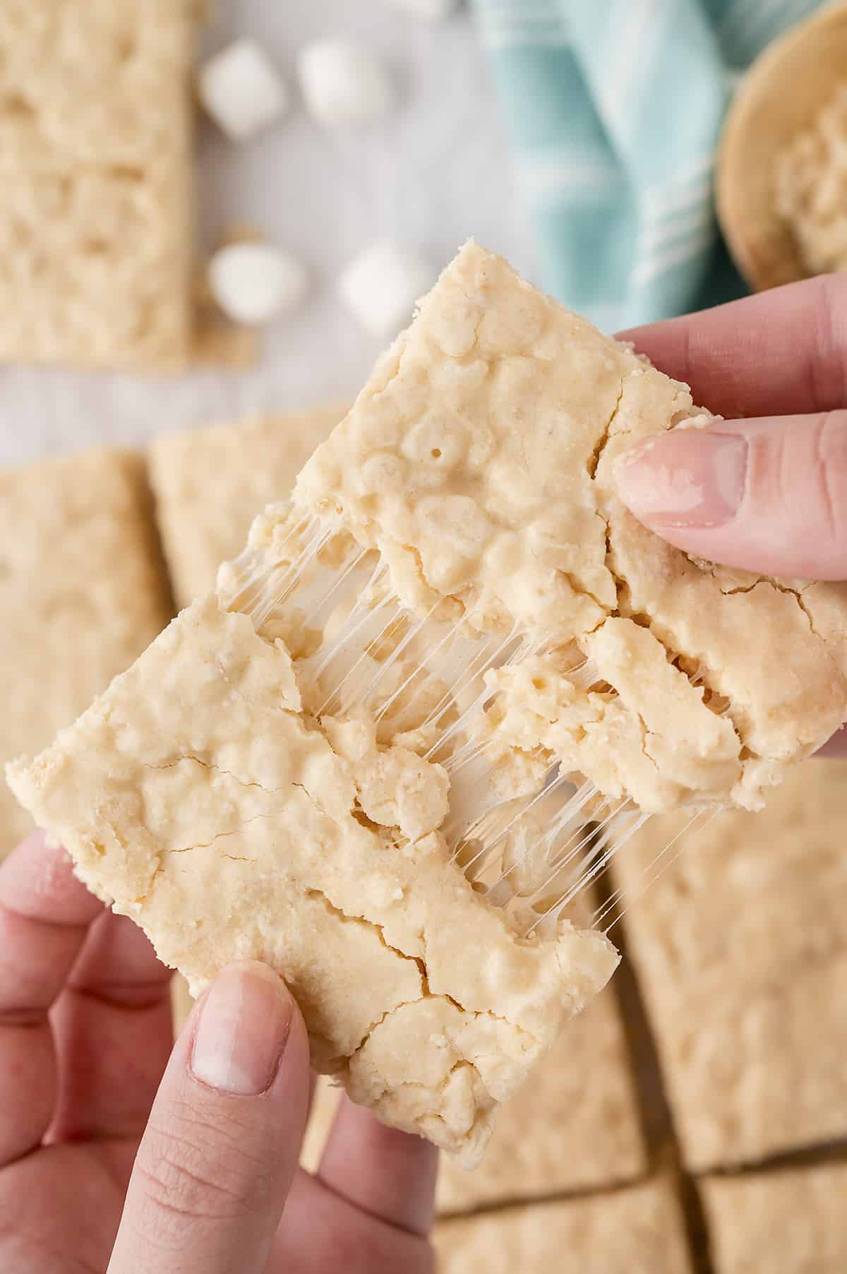 Hand pulling apart a browned butter rice krispie treat.