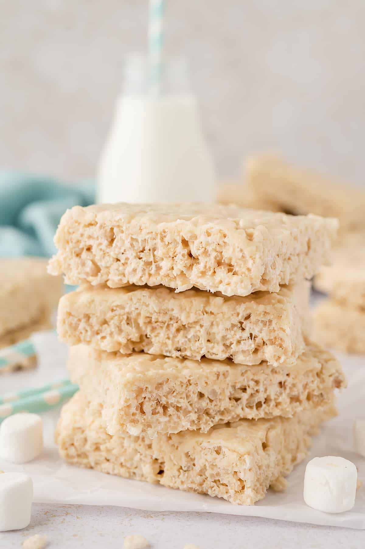 Stack of rice krispies treats in front of jar of milk.