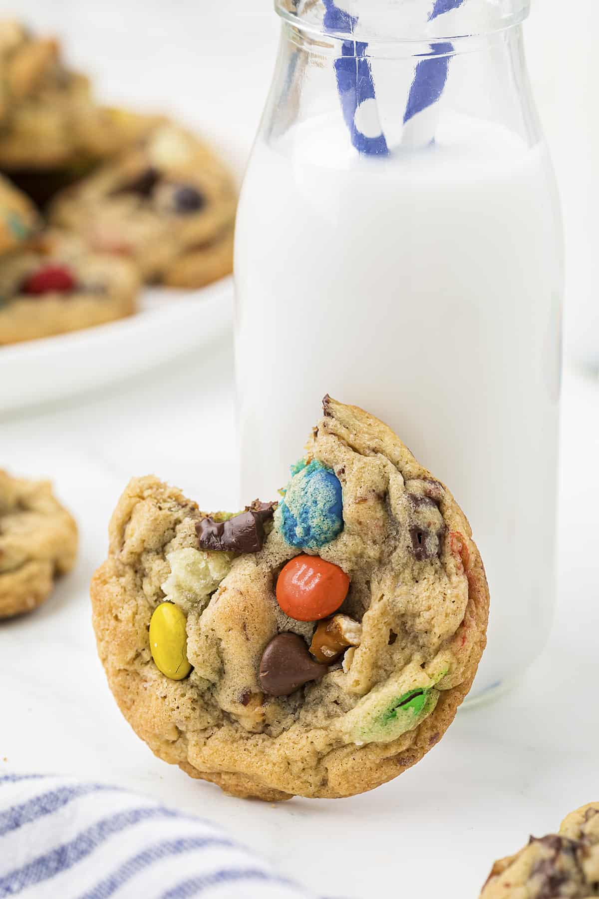 Cookie with a bite taken out of it against a jar of milk.