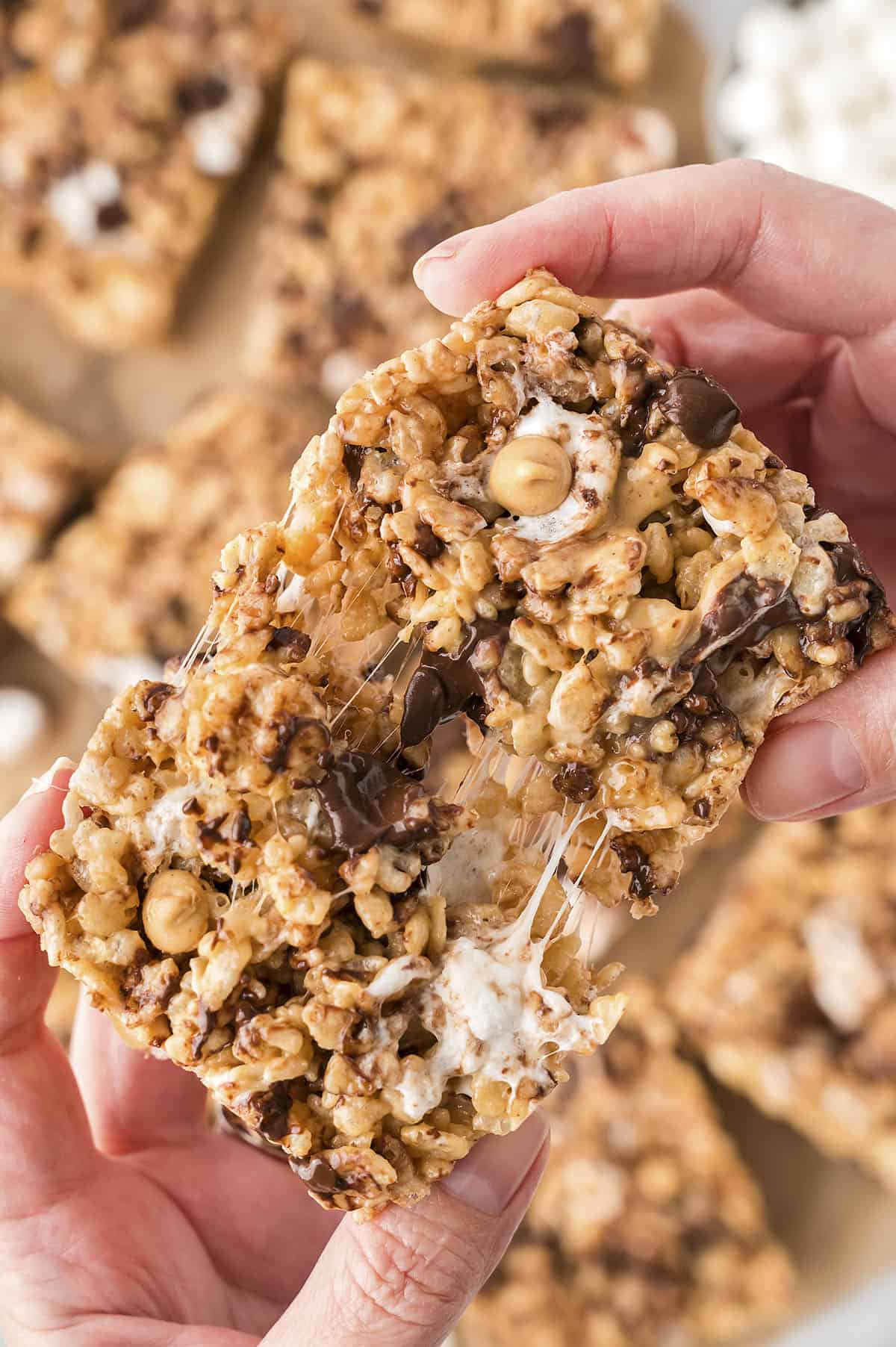 Hand pulling apart of a chocolate peanut butter rice krispie treat.