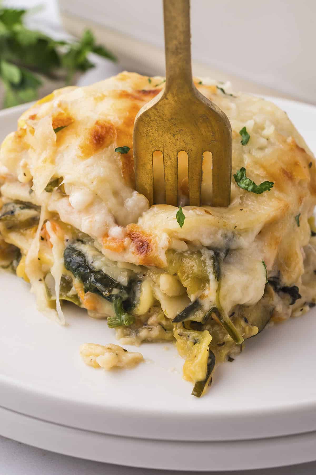 Fork in a slice of veggie lasagna.