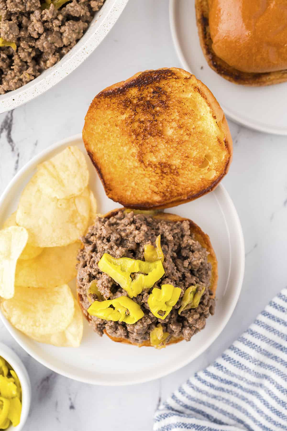 Sloppy joe on bun with pepperoncini peppers.