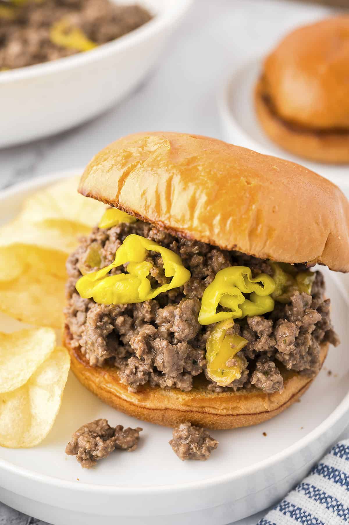 Mississippi sloppy joe on bun on white plate with chips.