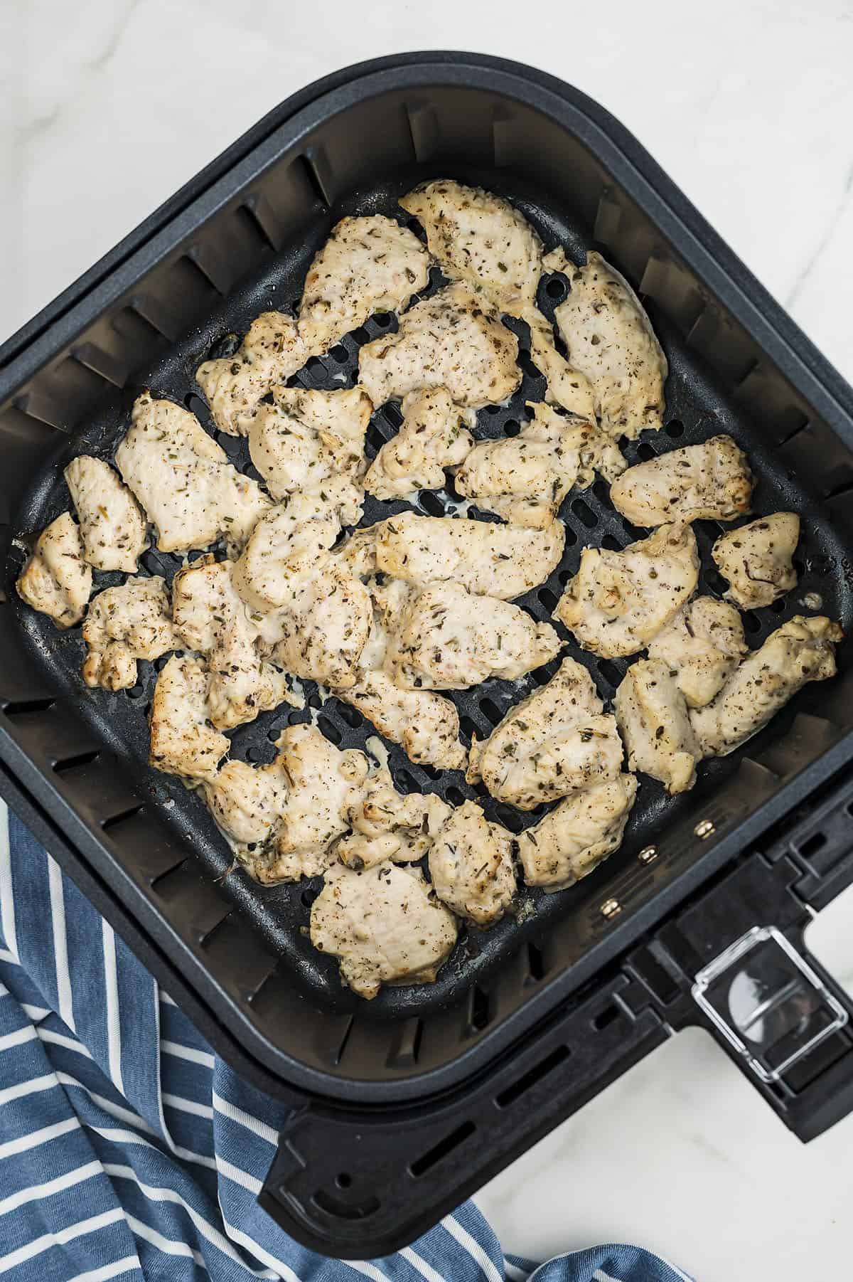 Cooked Greek chicken in air fryer basket.