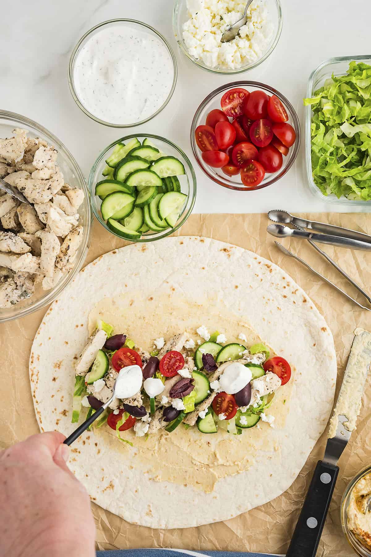 Ingredients for Greek chicken wrap layered on tortilla.