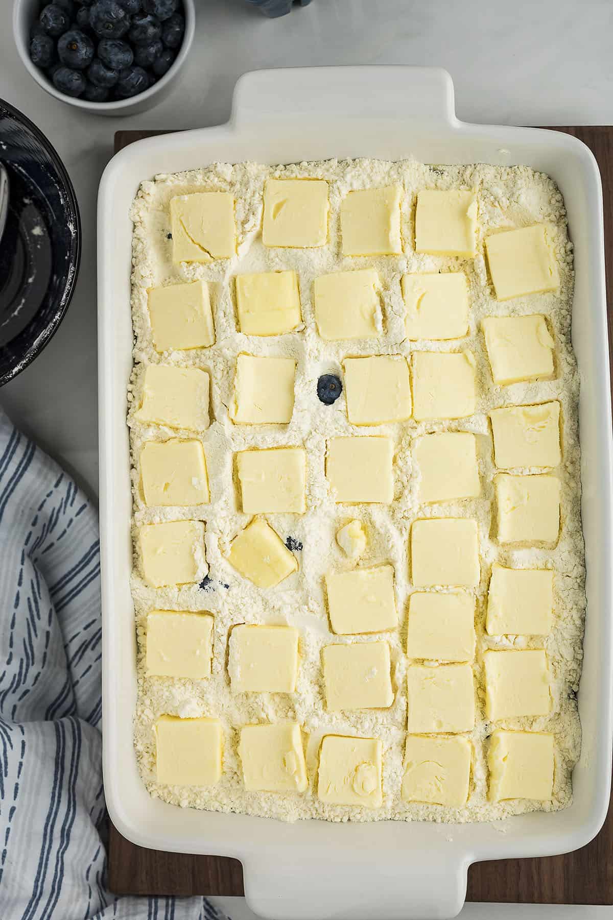 Ingredients for lemon blueberry dump cake in a white baking dish.