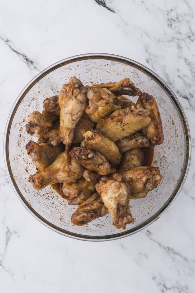 Chicken wings in glass bowl topped with hot honey glaze.