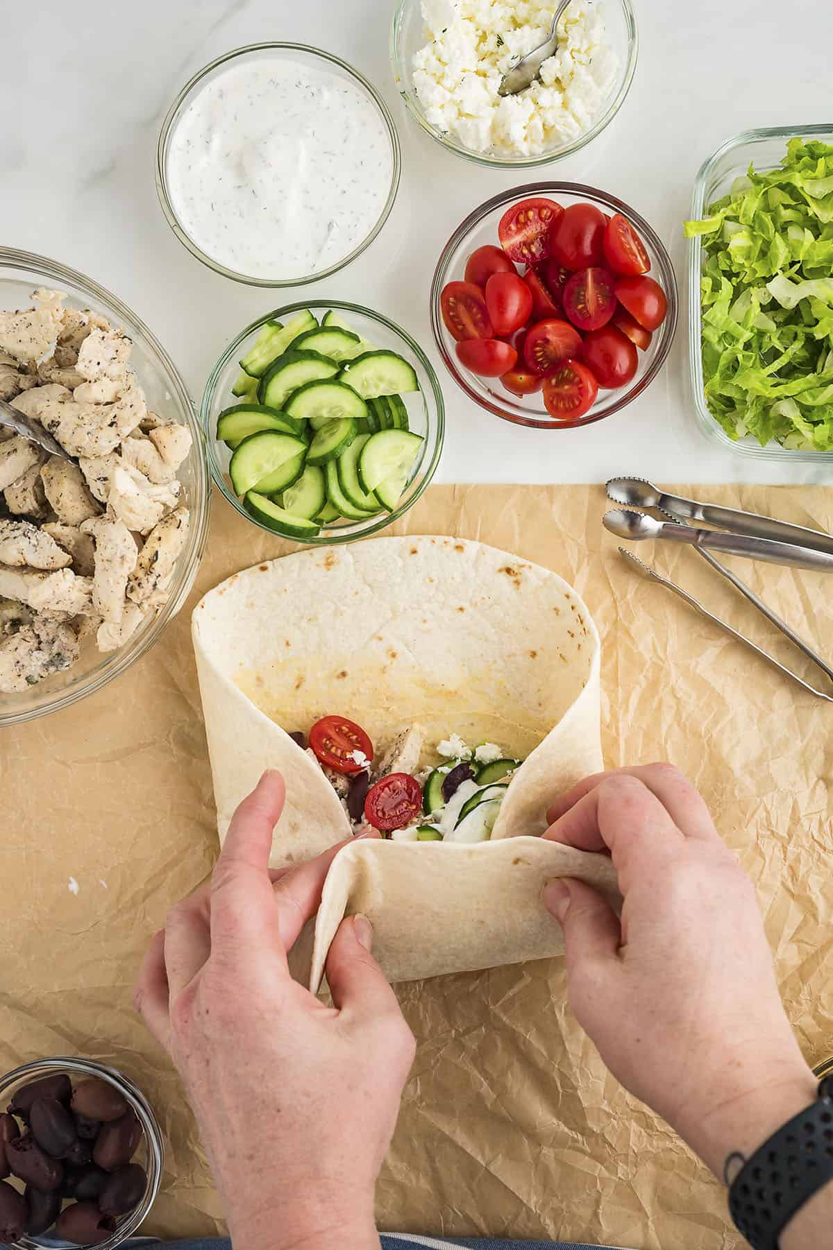 Woman's hands rolling up a tortilla filled with chicken and vegetables.