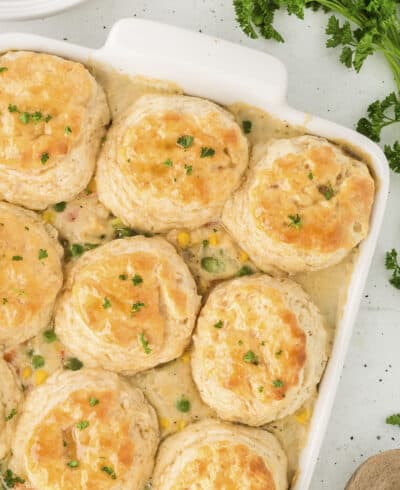 Chicken pot pie with biscuits in white casserole dish.