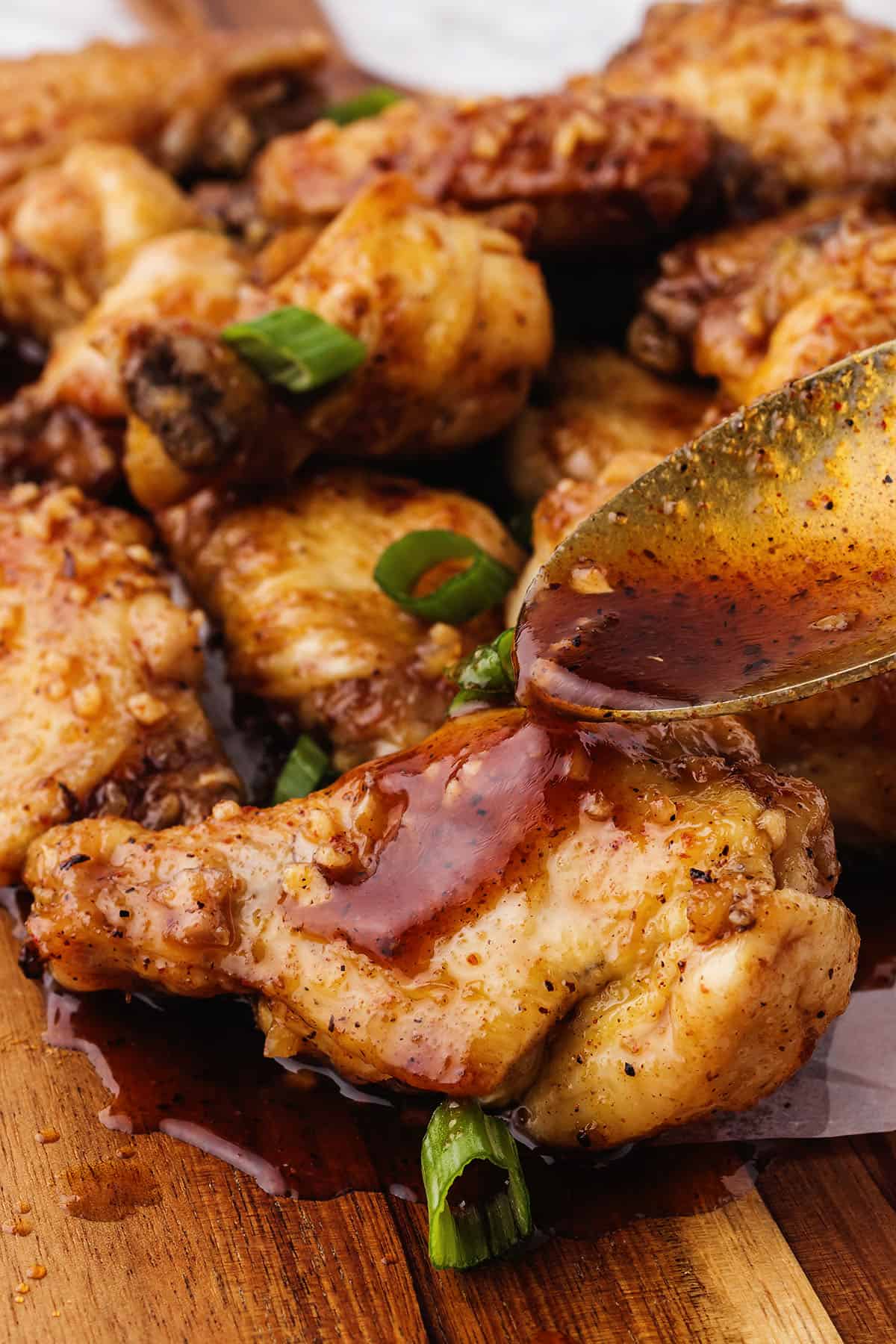 Spoon drizzling honey hot glaze over chicken wings.
