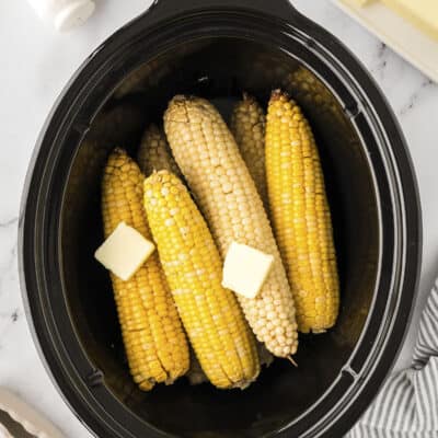 Corn on the cob in a crockpot topped with butter.