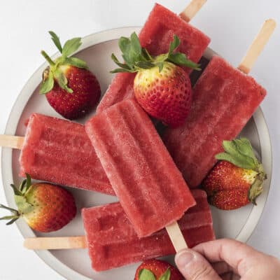 Hand grabbing a homemade strawberry popsicle.