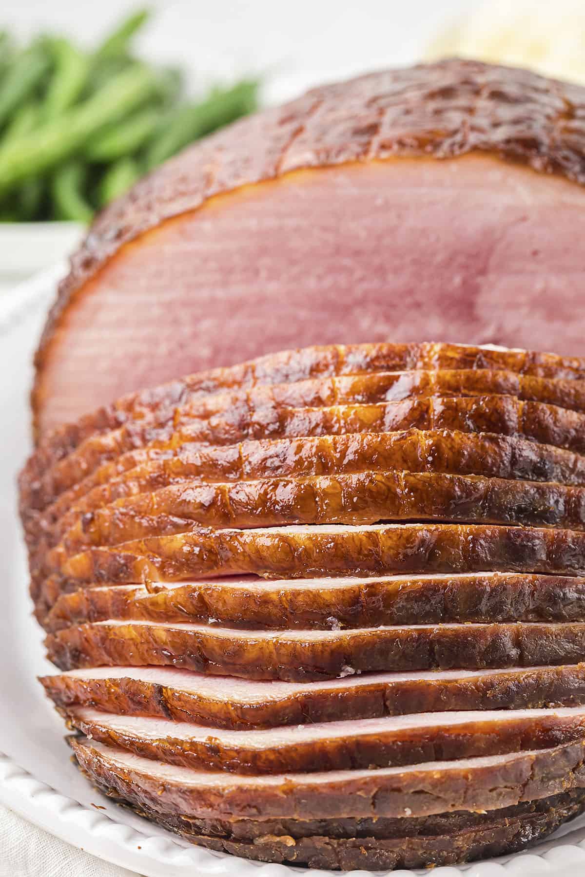 Sliced honey glazed crockpot ham on serving platter.