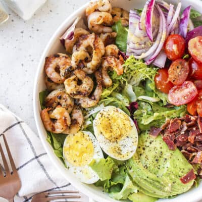 Overhead view of grilled shrimp salad in white salad bowl.
