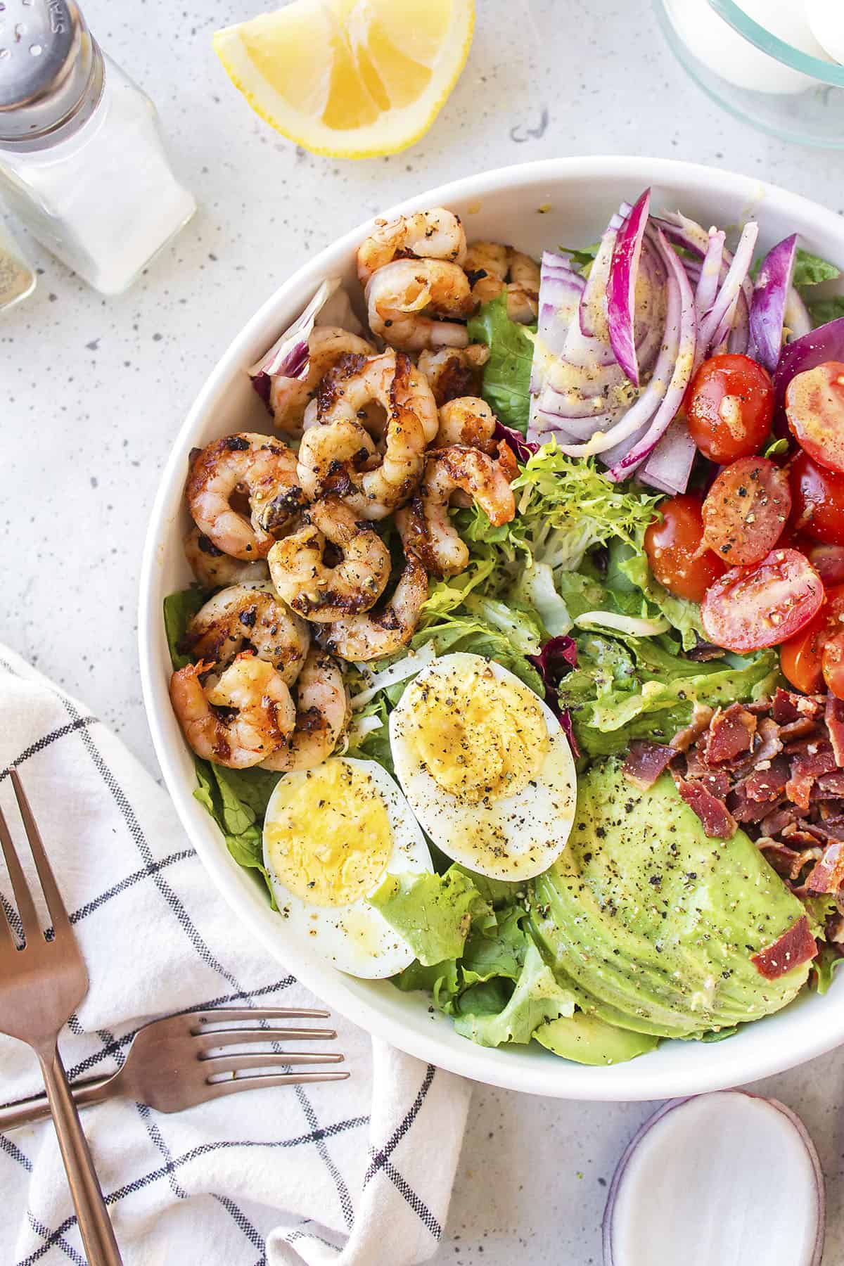 Overhead view of grilled shrimp salad in white salad bowl.