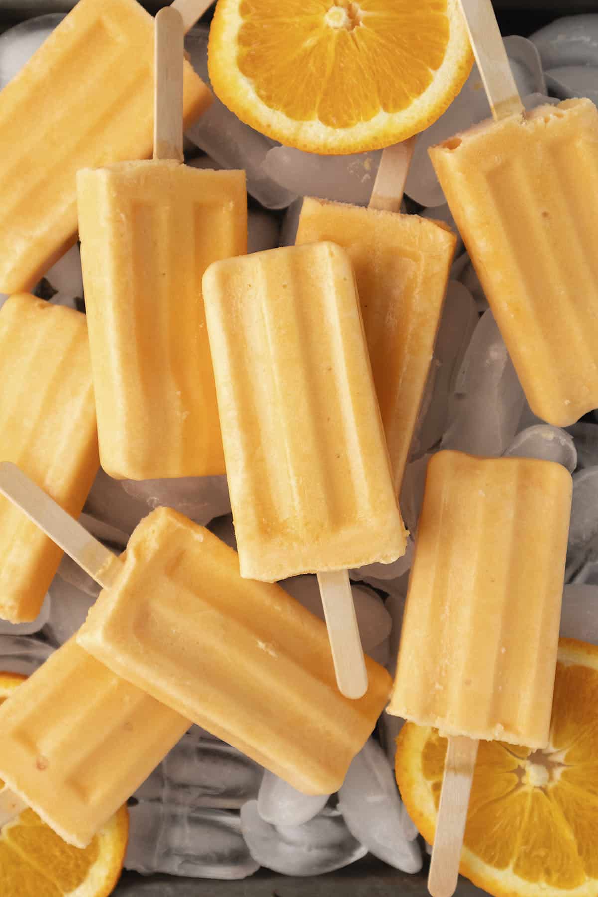 Orange creamsicle popsicles on pile of ice.