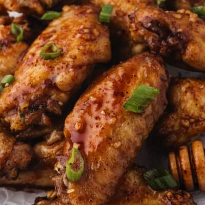Close up of hot honey chicken wings piled on platter.