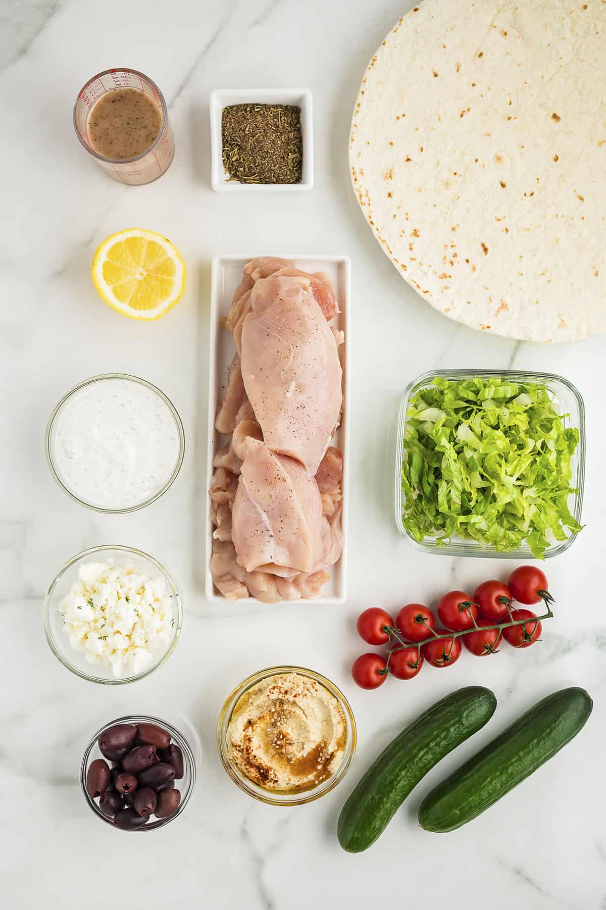 Ingredients for Greek chicken wraps on white countertop.