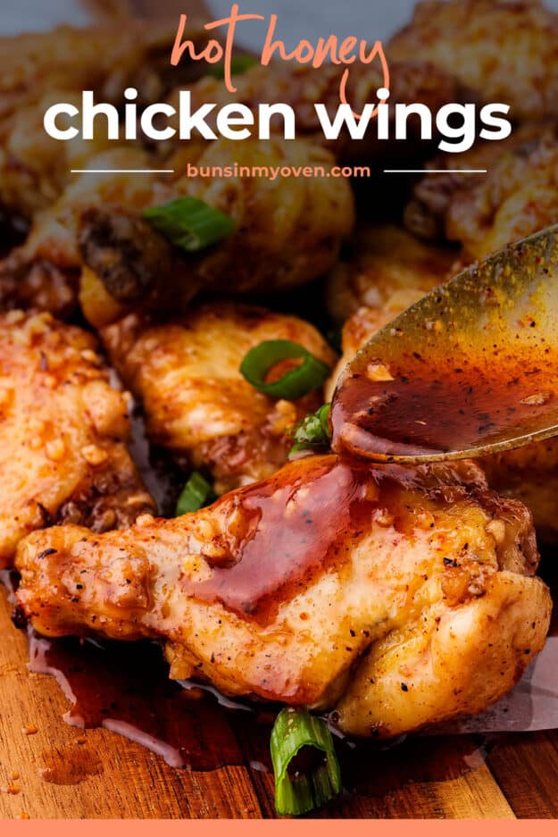 Spoon drizzling hot honey glaze over chicken wings.