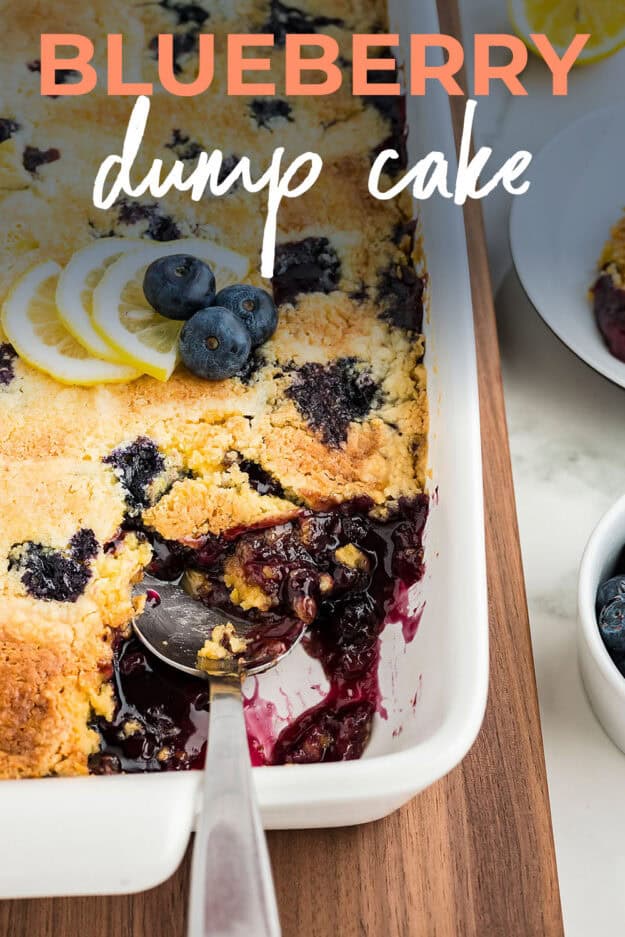 Blueberry dump cake in white baking dish with spoon.