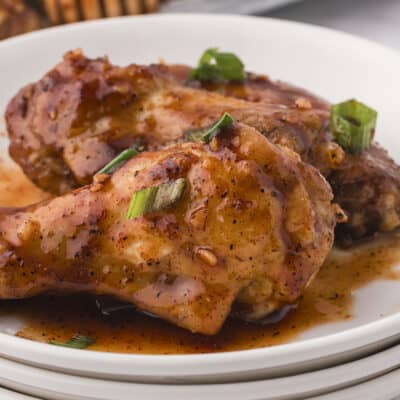 Chicken wings on stack of white plates.