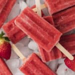 Strawberry popsicles piled on ice.