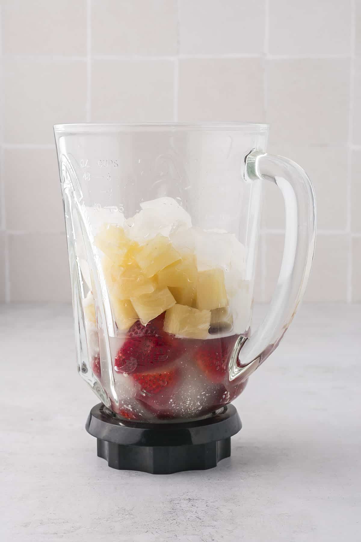 Ingredients for strawberry pineapple smoothie in blender.