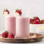 Strawberry pineapple smoothies in glass on wooden board.