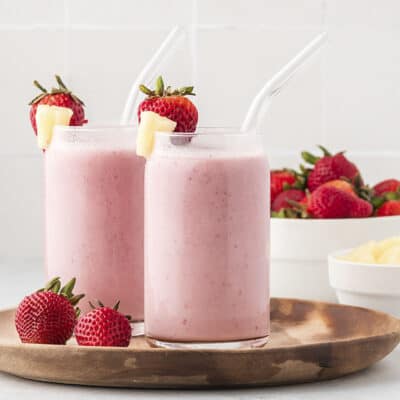 Strawberry pineapple smoothies in glass on wooden board.