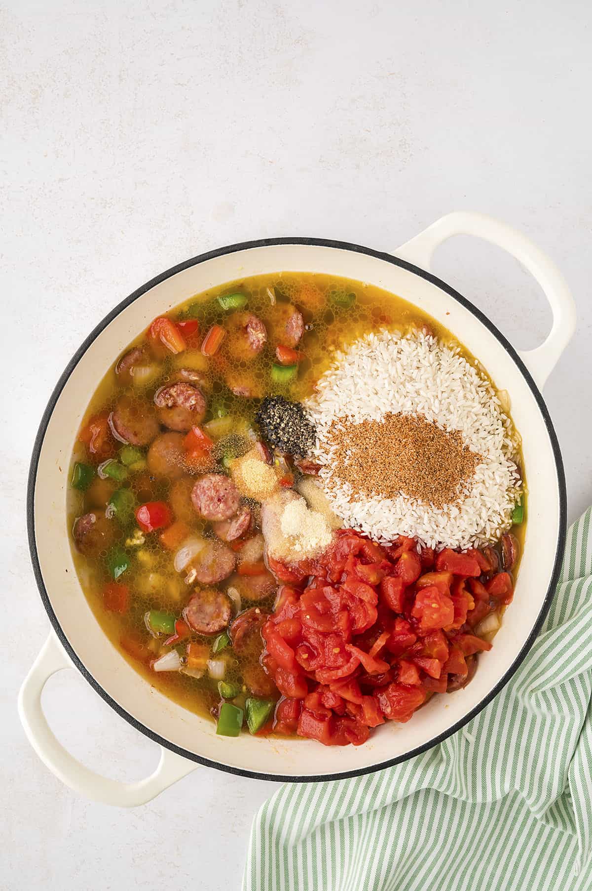 Chicken broth, rice, and tomatoes added to pot with sausage.