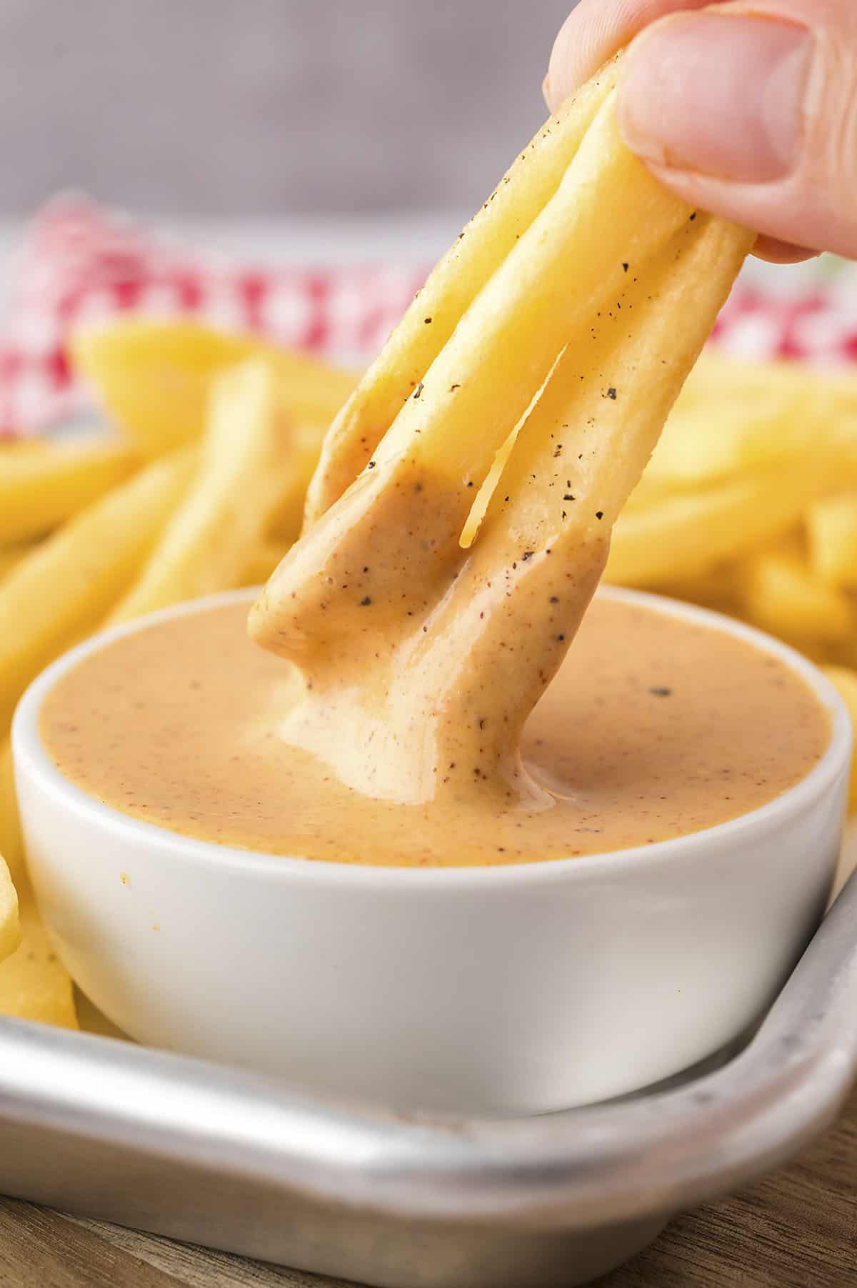 French fries dipped in small bowl of smashburger sauce.