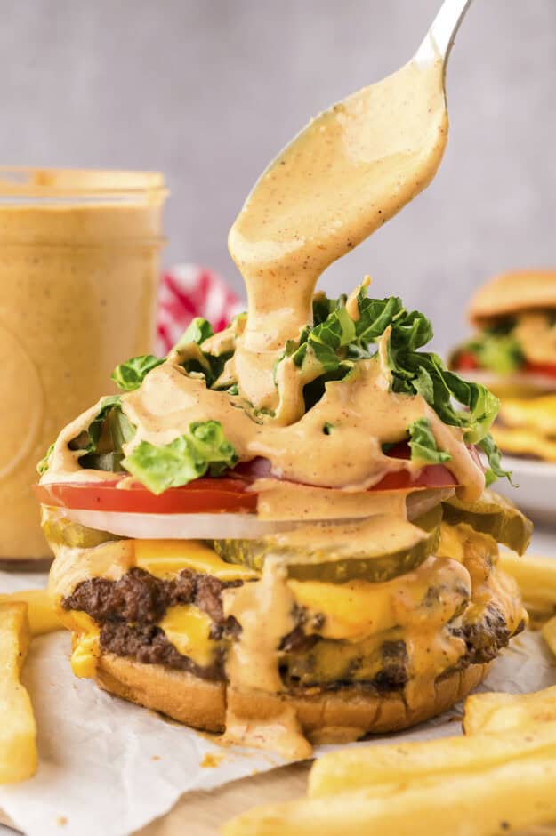 Sauce being drizzled over a smash burger.