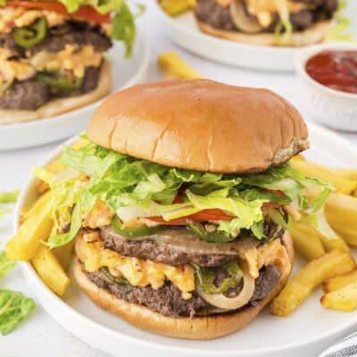 Pimento cheese smash burgers on white plates.