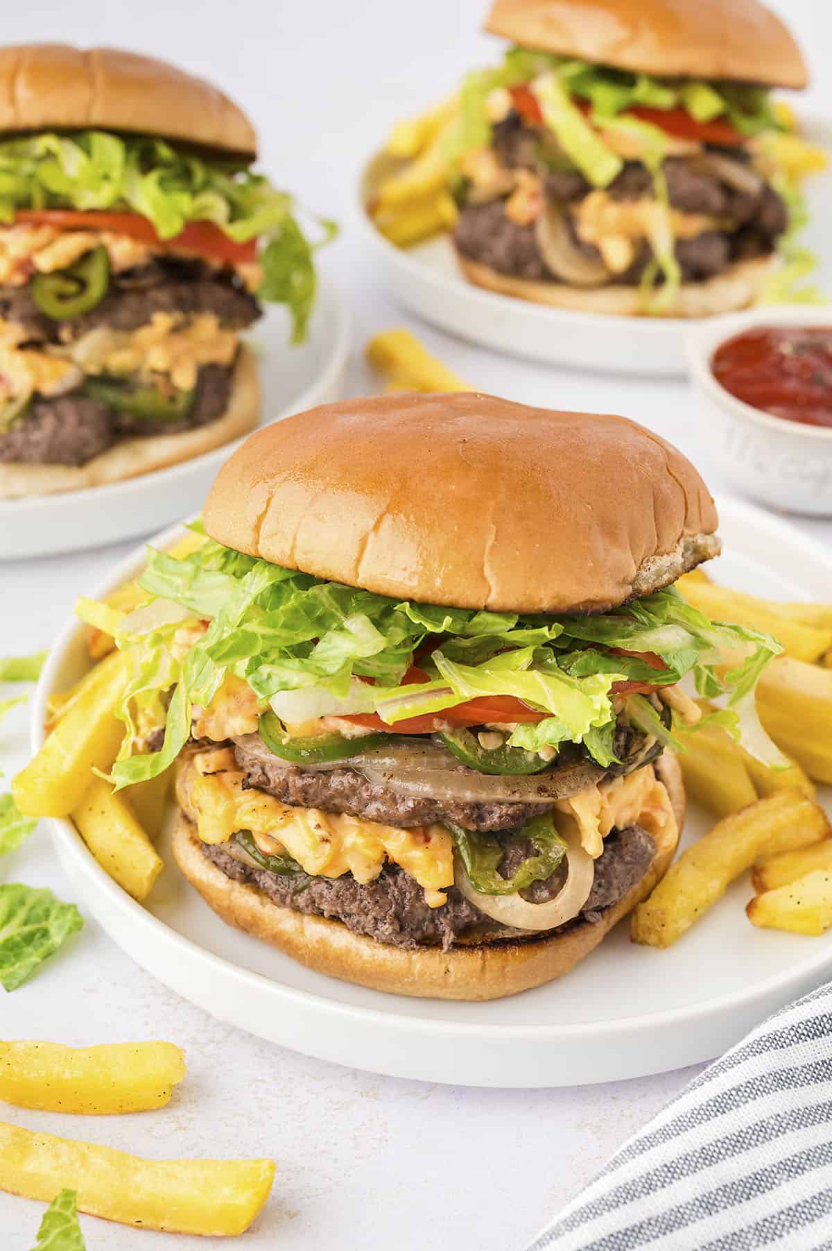 Pimento cheese smash burgers on white plates.