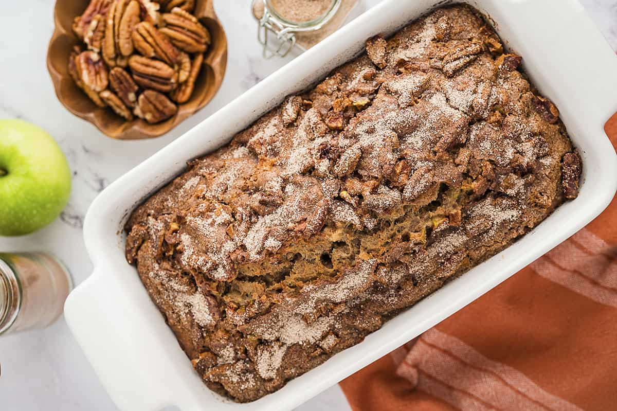 Apple bread in white ceramic loaf pan.