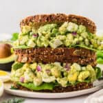 Avocado egg salad sandwiches stacked on small plate.