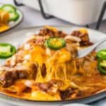 Forkful of cheese enchiladas topped with chili.