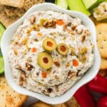 Olive spread in white bowl on veggie and cracker tray.