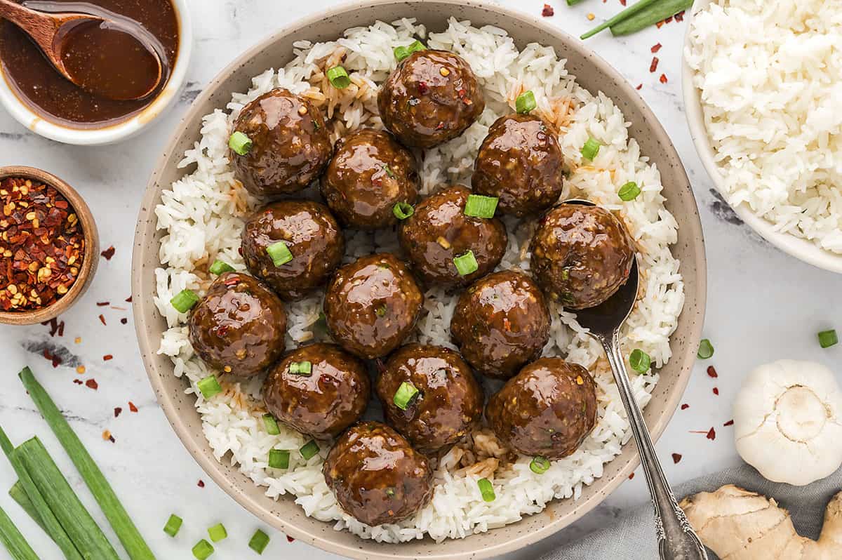Plate full of firecracker meatballs over rice.